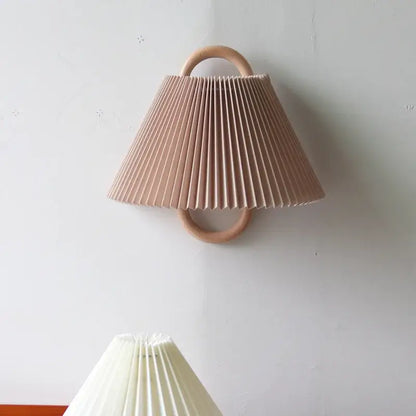 Soft blush pink pleated cream shade on a retro beech wood wall sconce wood wall lamp for bedroom use