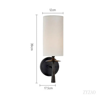 A sleek black metal brass wall lamp with a cylindrical off-white fabric shade and slender stem for bedroom decorbites brass wall lamp