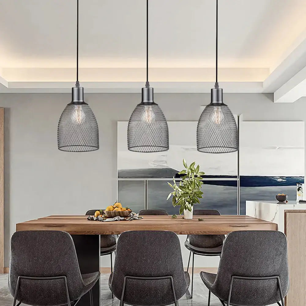 Three black metal decorbites cage bell pendant lights hang above a wooden dining table as pendant light decor