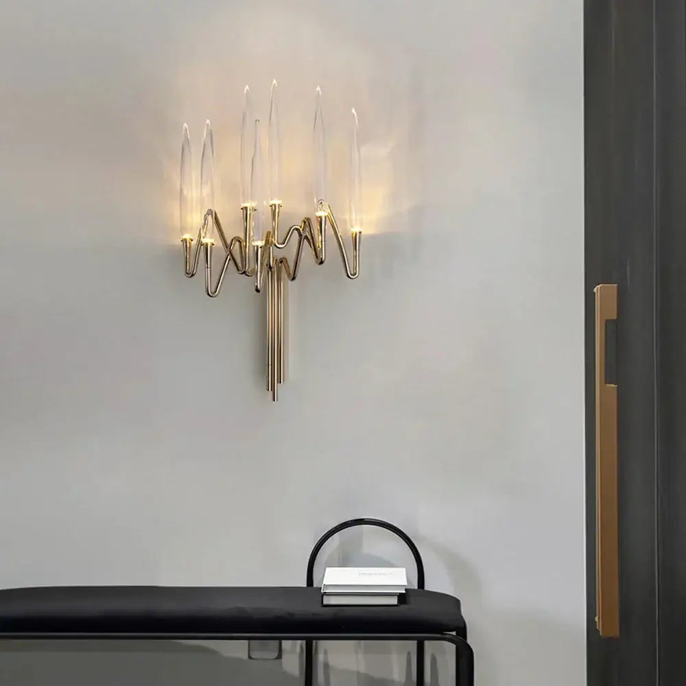 Gold-toned crystal candle wall sconce with five transparent glass candle-like arms and wavy metallic base for decorbites candle wall sconce