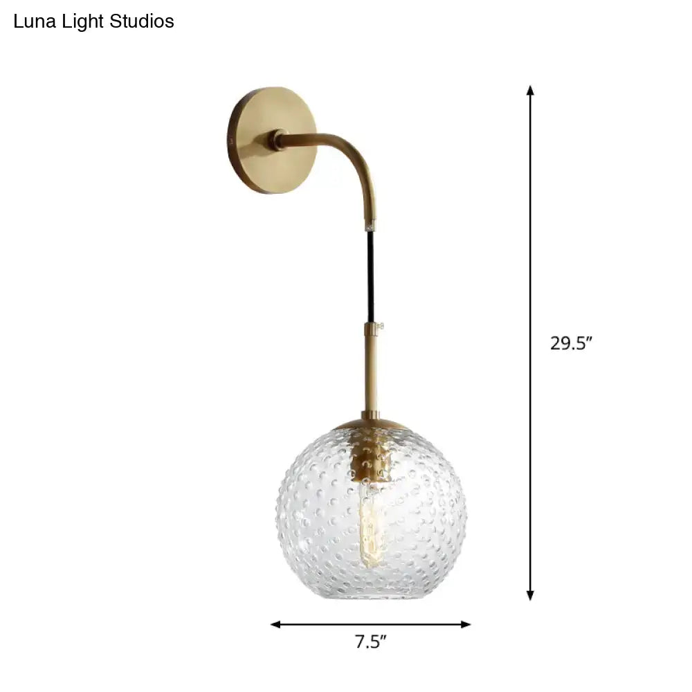 Brass-finished wall sconce with textured clear glass globe in pink yellow blue retro style for bedroom lighting