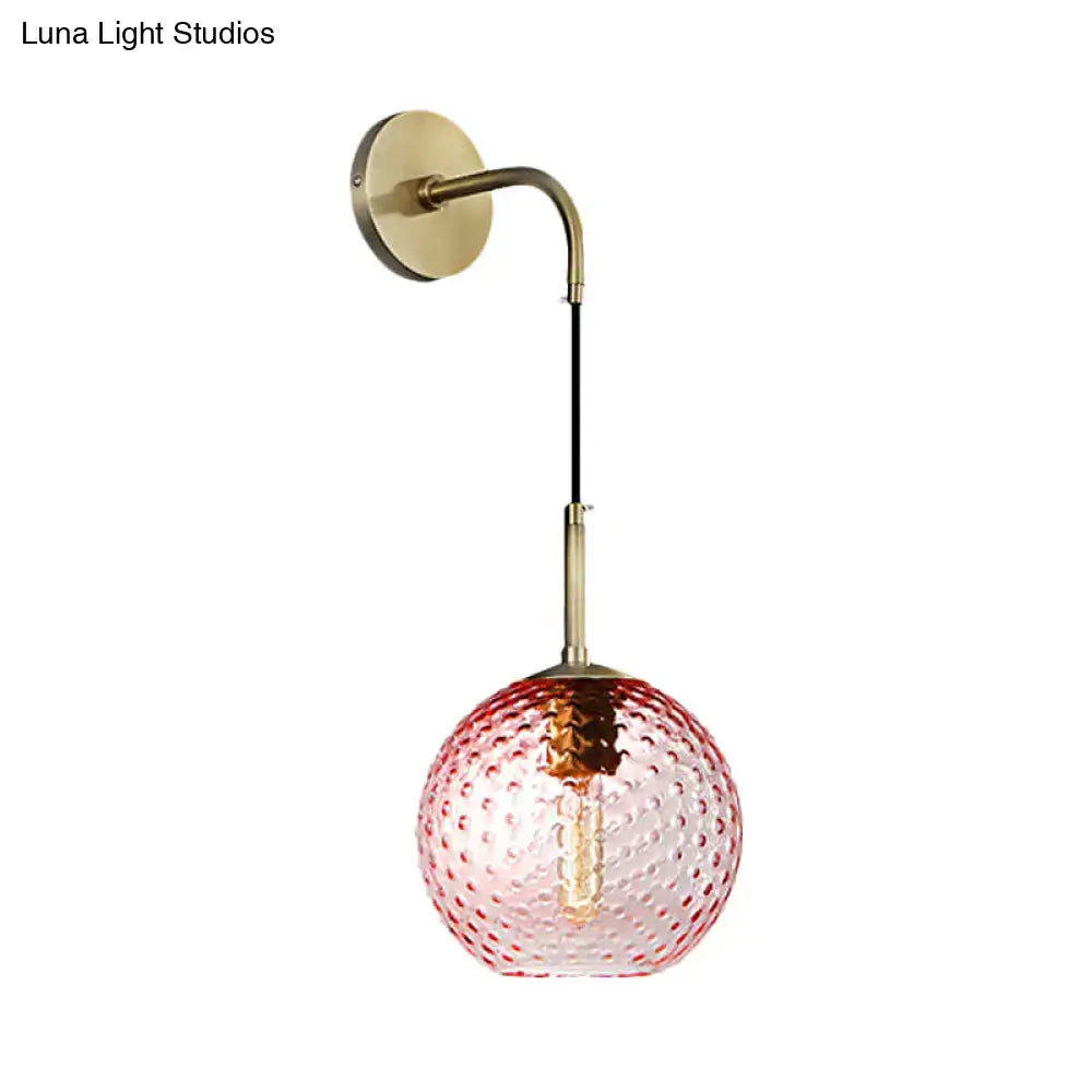 A delicate pink glass globe pendant light with bubble texture and brass hardware for pink yellow blue decor