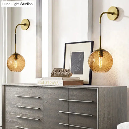 Gold-toned wall sconces with textured amber glass globes and brass arms for pink yellow blue bedroom lighting