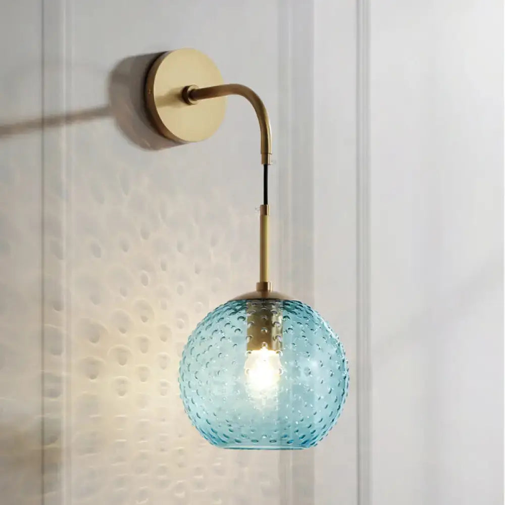 Retro blue glass globe wall lamp with textured light blue glass and brass accents featuring pink yellow blue hues