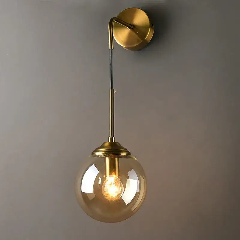 Retro brass and amber decorbites glass ball wall lamp with spherical amber glass globe and exposed bulb for bathroom use