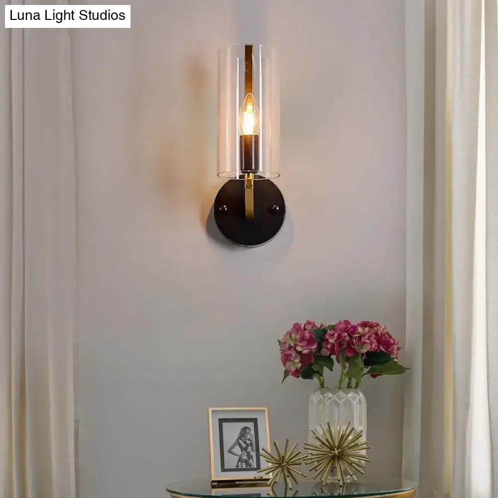 Modern wall light with black circular base, retro brass accents, and transparent glass sconce for bedroom use