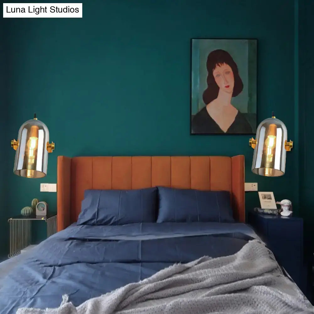 Pair of modern brass cloche sconce lights with warm glowing bulbs and blue glass for bedroom lighting
