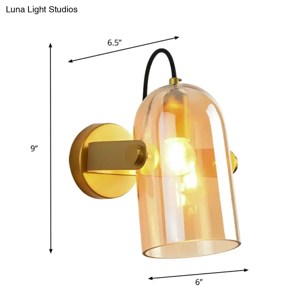 Retro brass cloche sconce light with amber glass dome, brass mount, and black cord for modern interior lighting