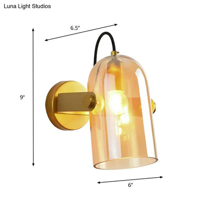 Retro brass cloche sconce light with amber glass dome, brass mount, and black cord for modern interior lighting