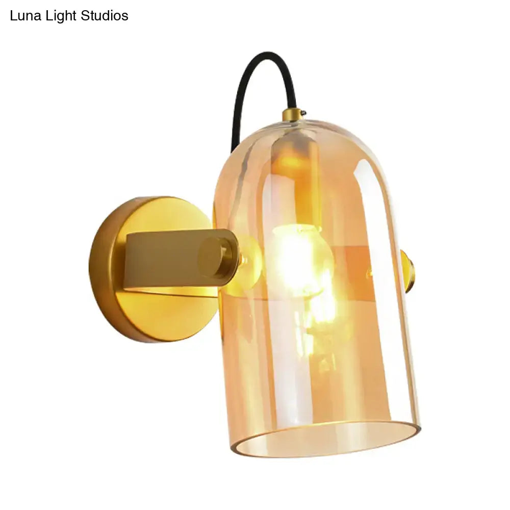 Warm amber glass bell-shaped sconce light with gold metal bracket and black cord in retro brass cloche sconce light design