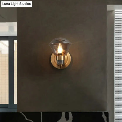 A warm-toned brass light fixture with a clear teardrop glass shade for bedroom featuring smoke gray amber accents