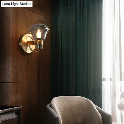 Brass-finished wall sconce with a faceted smoke gray amber glass shade for retro bedroom light fixture