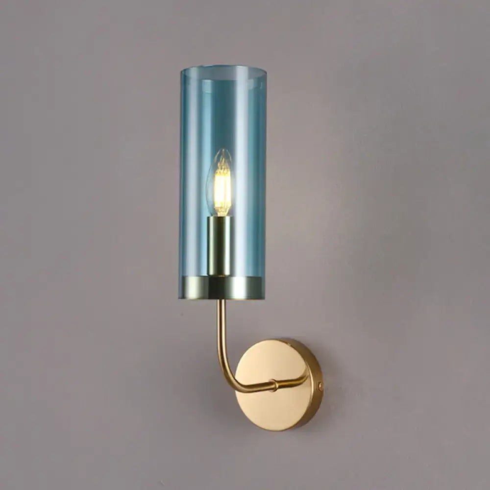 Blue cylindrical glass wall mount lamp with brass-finished metal base and arm for living room use