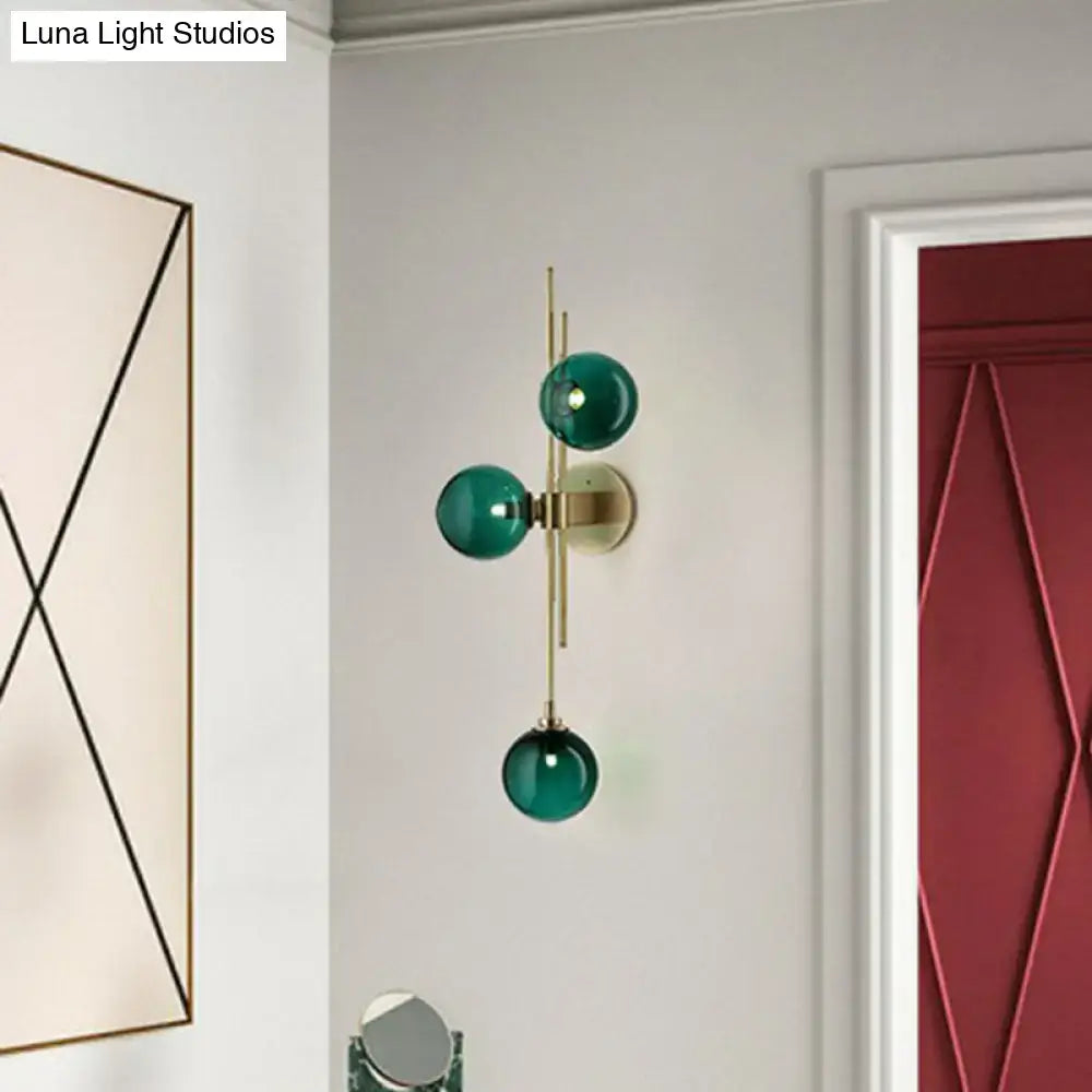 Retro brass wall sconce with three emerald green glass globes and brass accents for dining room lighting