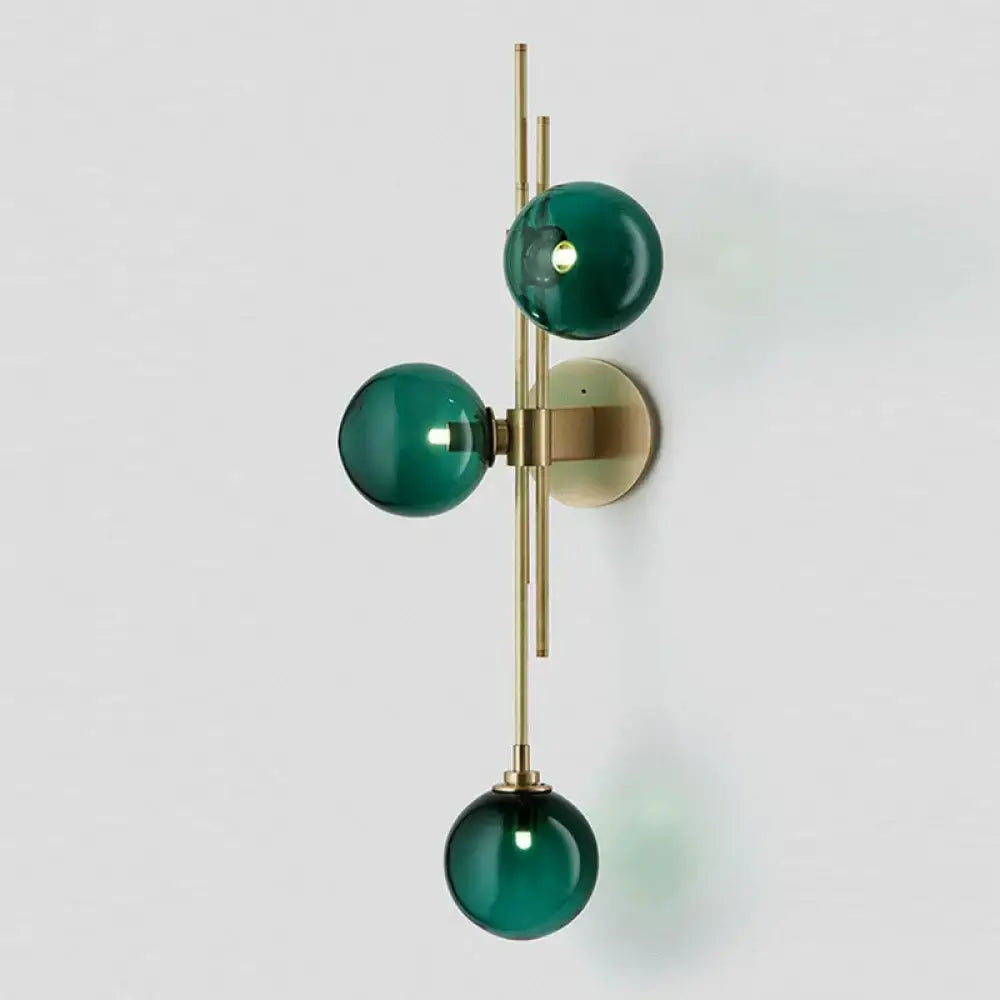 Retro brass wall sconce with three emerald green glass globes suspended from a slender brass wall frame for dining room