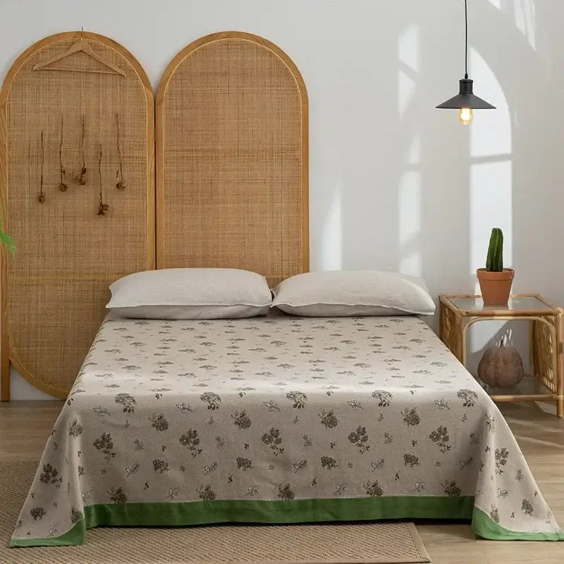 Retro daisy olive and teal decorbites cotton throw blanket with beige floral bed sheet and green border draped neatly over mattress
