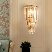 Gold-toned wall mounted sconce with three lights and cascading clear crystal rods direct wired electric design