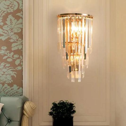 Gold-toned wall mounted sconce with three lights and cascading clear crystal rods direct wired electric design