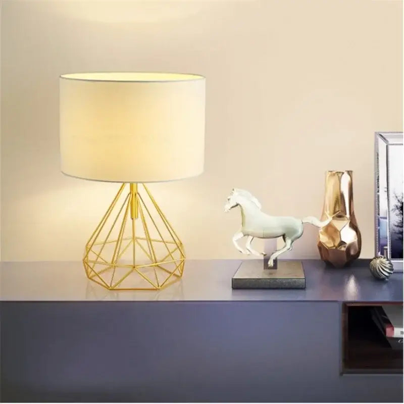 Gold geometric table lamp with wire base and cream cylindrical shade ideal for study room lighting