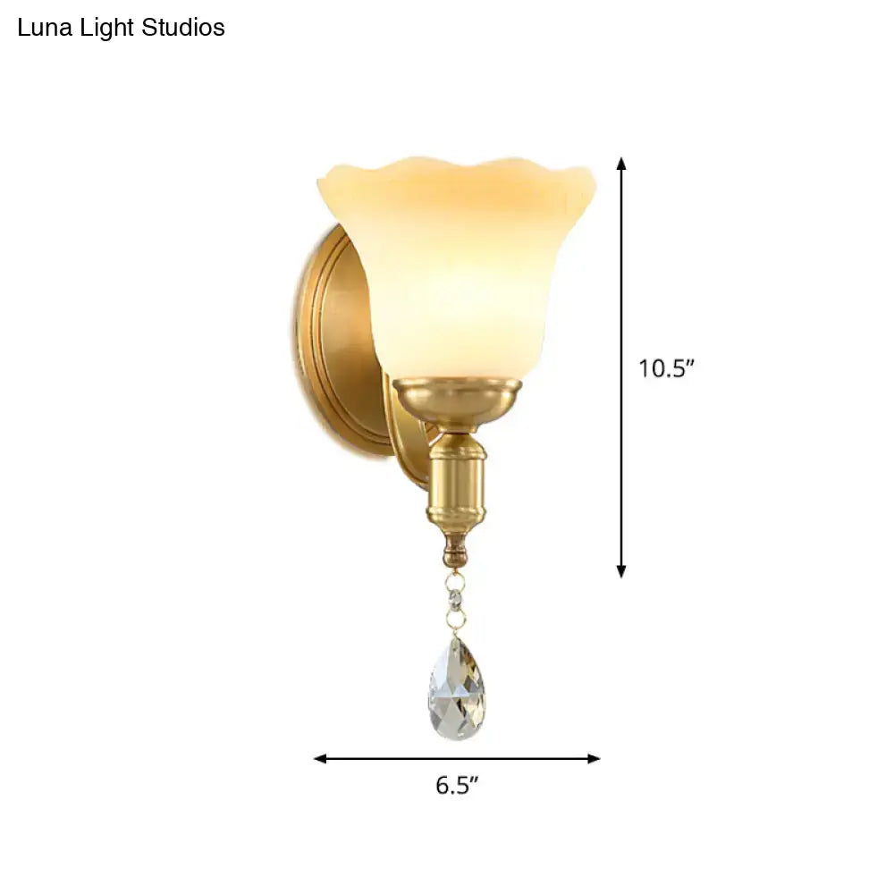 Retro gold wall lamp featuring a blossom opaque glass shade with a dangling teardrop crystal sconce for bedroom use