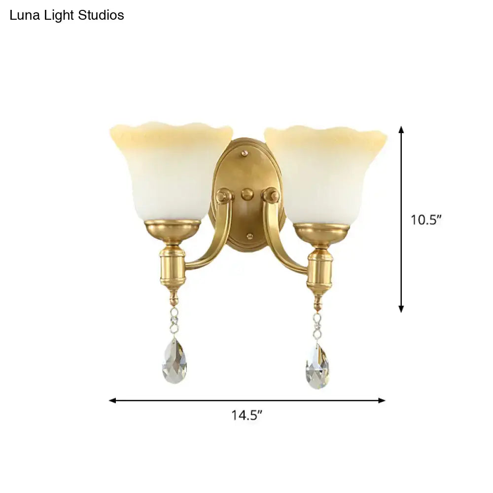 Gold-finished wall lamp with two cream scalloped blossom opaque glass shades and crystal teardrop pendants for bedroom use