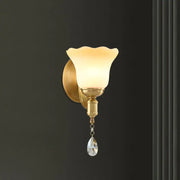 Gold-toned retro wall lamp with blossom opaque glass shade and crystal teardrop for elegant bedroom use