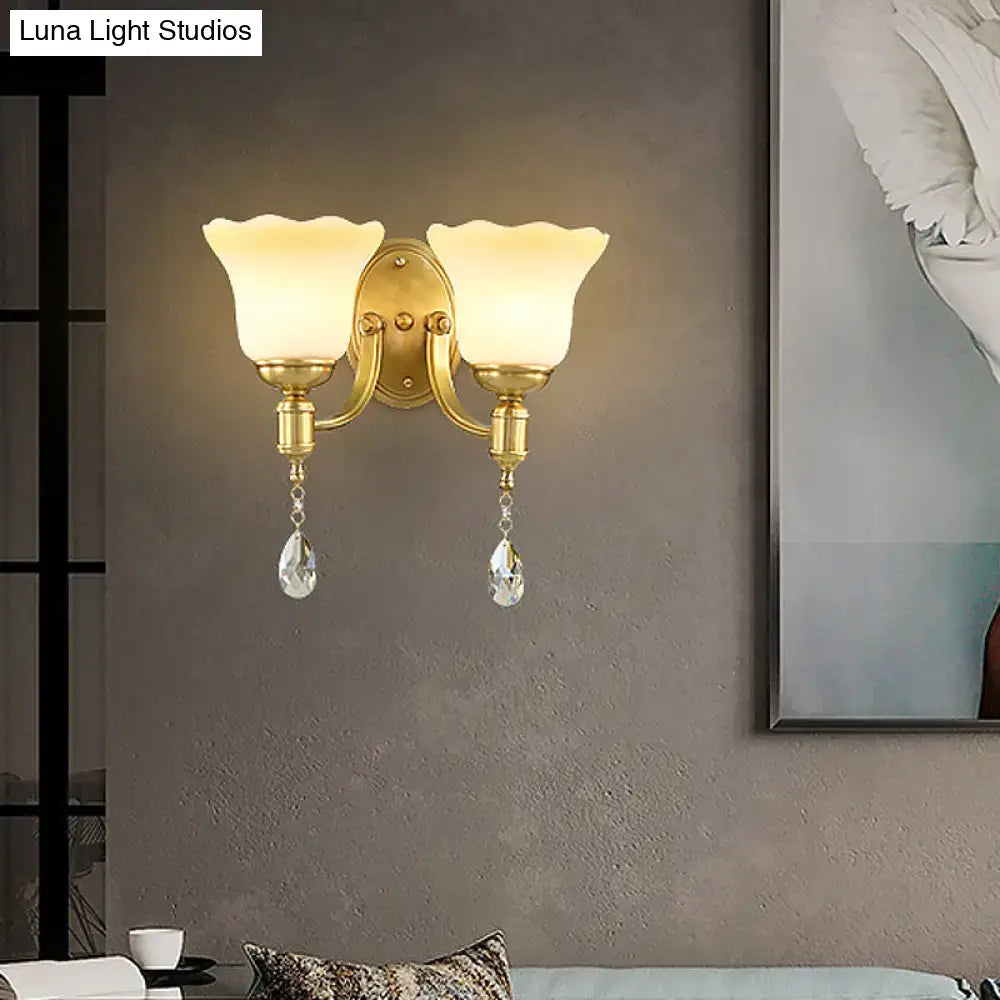 Gold-toned retro wall lamp with two cream blossom opaque glass shades and crystal teardrop pendants for bedroom use