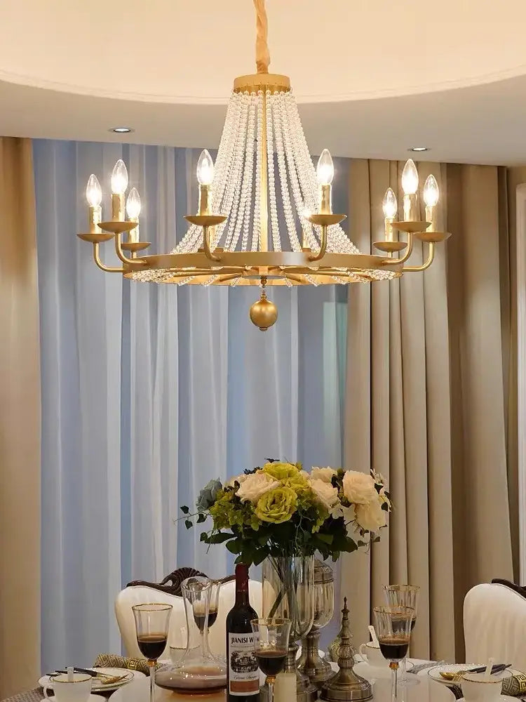 Gold-toned decorbites crystal chandelier with cascading crystal strands and candle-style bulbs for dining room lighting