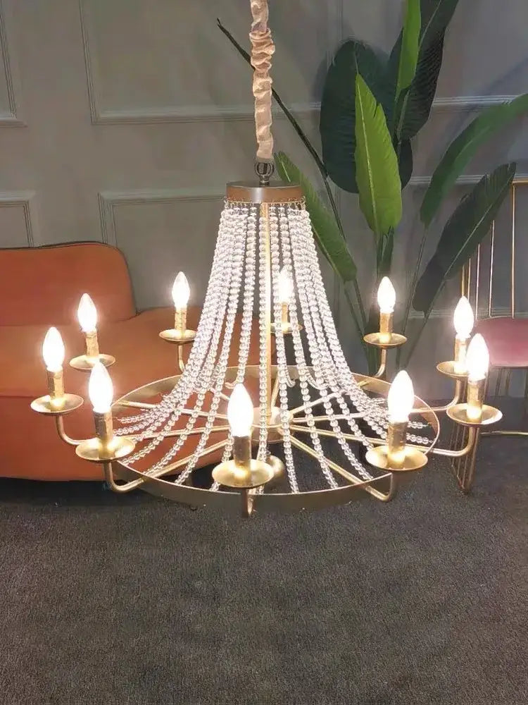A gold-toned decorbites crystal chandelier with cascading beads and candle-style bulbs for dining room decor
