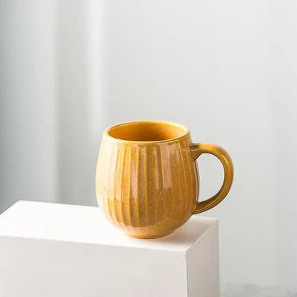 A warm amber ceramic coffee mug with vertical ribbed texture and smooth glossy gradient glaze finish