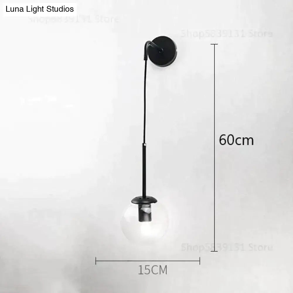 Black metal wall lamp with slender curved arm and clear glass globe bulb for nordic retro modern bedroom lighting