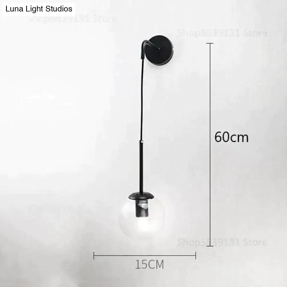 Black metal wall lamp with a slender curved arm and clear glass bulb for retro modern glass bedroom lighting