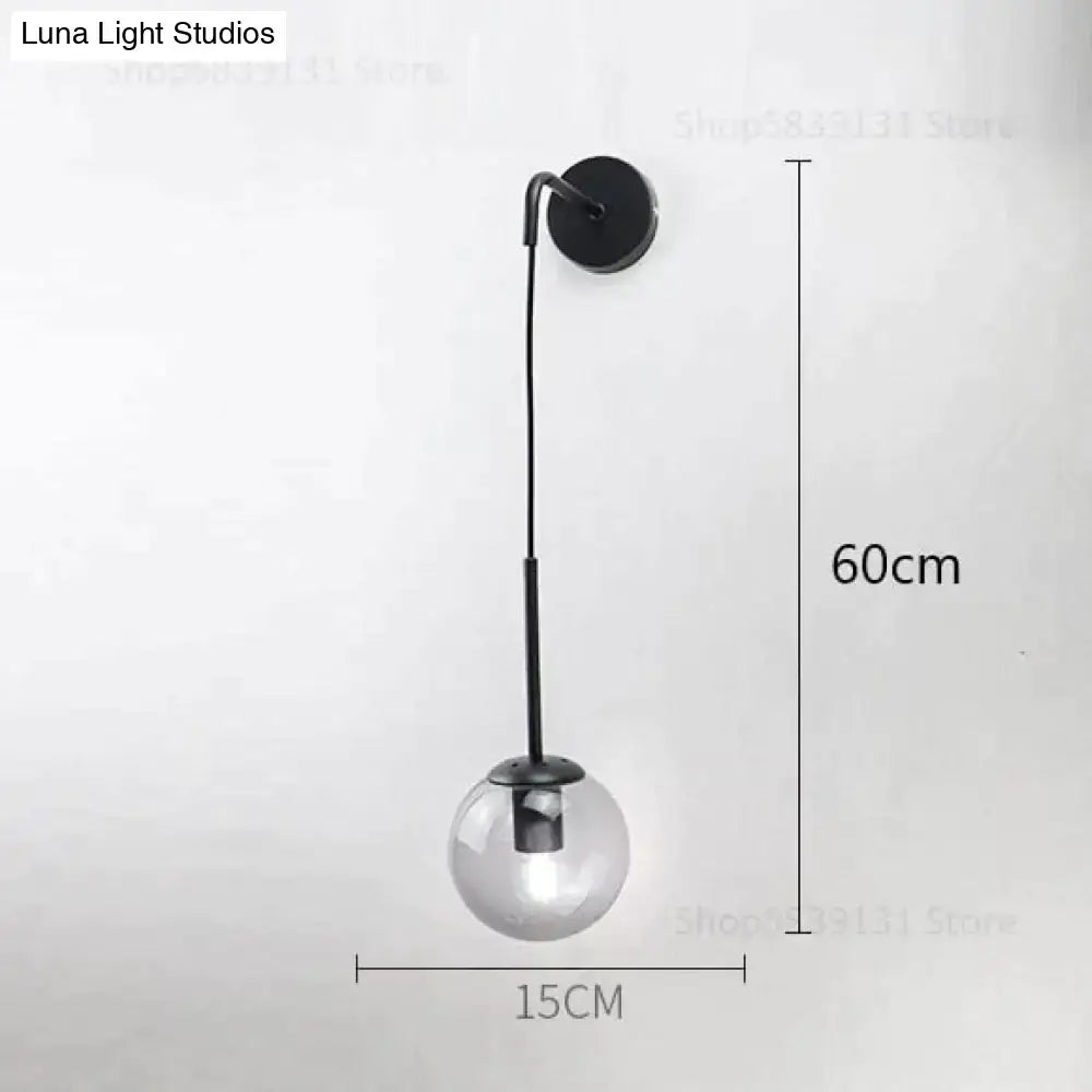 Modern black wall lamp with slim metal arm and clear glass globe designed for nordic retro modern bedroom lighting