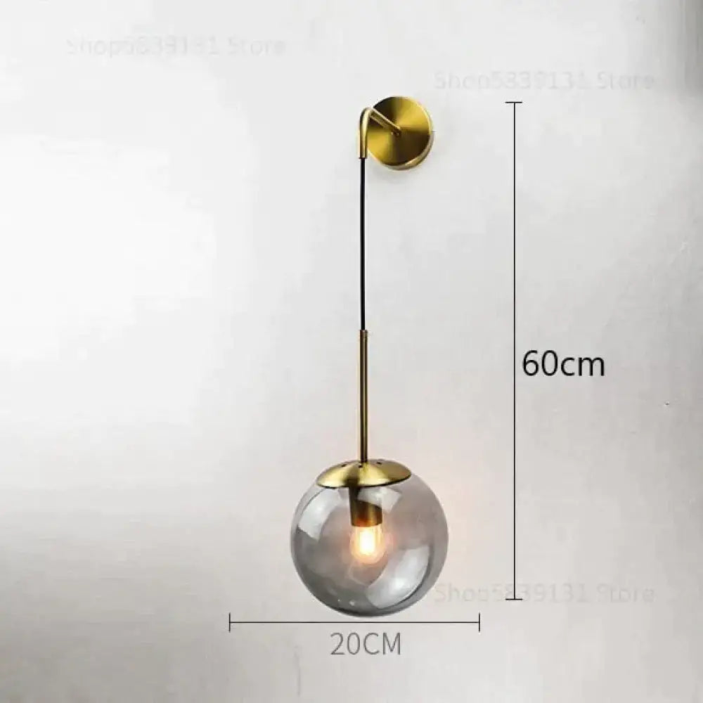 A brass-finished retro modern glass wall lamp with a smoked globe and exposed bulb for nordic bedroom lighting