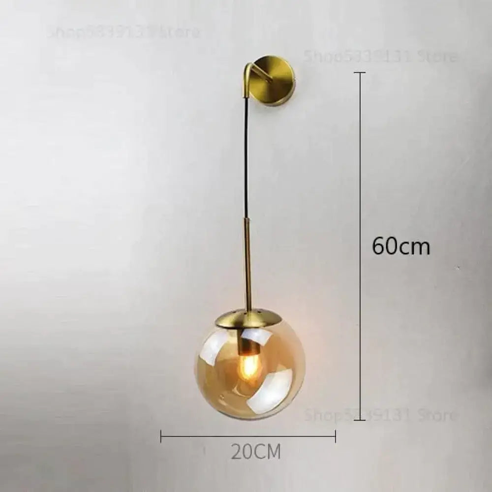A modern brass-finished wall lamp with a spherical amber retro modern glass globe and an elegant curved arm for bedroom lighting