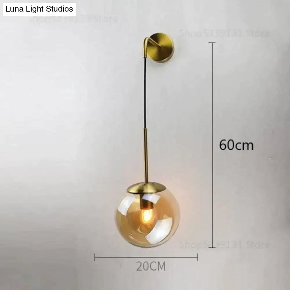 Gold-toned spherical glass pendant wall lamp with brass mount and black cord for nordic retro modern bedroom lighting