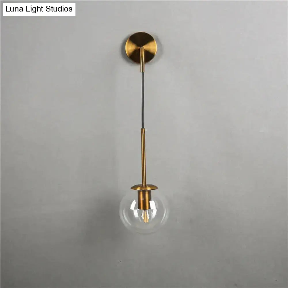Gold-toned retro modern glass wall lamp with clear globe and brass stem for nordic retro modern bedroom lighting