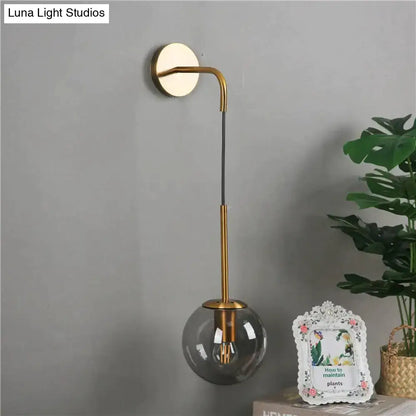 A sleek gold-toned nordic retro modern wall lamp with a curved arm and smoked glass globe for bedroom lighting