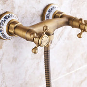 Antique brass double-handle shower faucet with ornate blue and white ceramic escutcheons for wall mount use