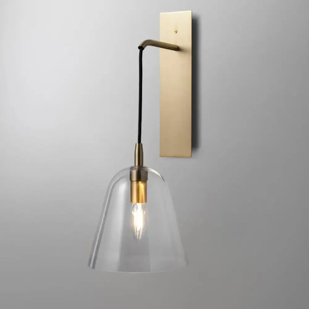 Retro style brass wall light with clear glass bell shade and black cord featuring e14 bulb base for bedroom sconce use