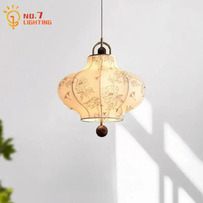 A cream fabric retro pendant light with intricate floral embroidery and dark wooden base by decorbites wabi-sabi