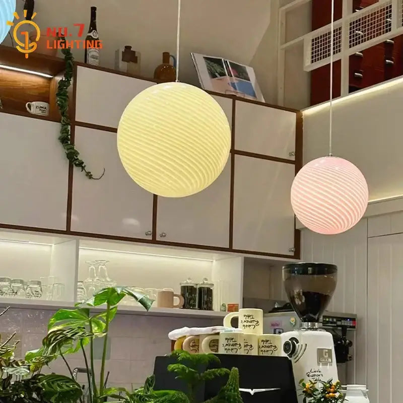 Cream and pink spherical glass pendant lights with ribbed amber glass shades for dining room lighting