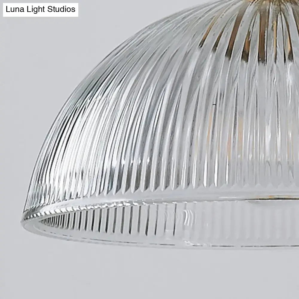 Clear glass dome pendant light with vertical ribbed glass texture and gold-toned fixture for dining room use