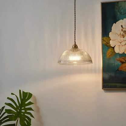 Clear ribbed glass chandelier pendant lights with a brass finish and dark braided cord for bedroom use