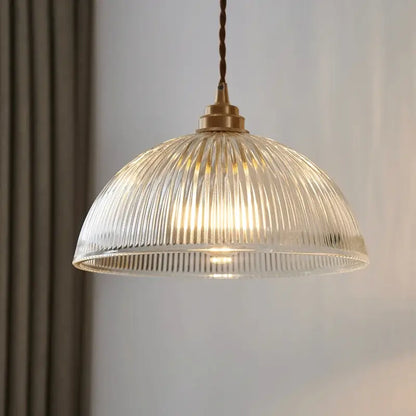 A warm-toned ribbed glass chandelier pendant light with brass finish and twisted cord for bedroom pendant lights