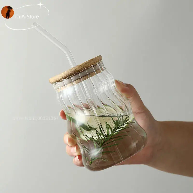 Clear ribbed glass cup with bamboo lid and lip straw filled with water and fresh rosemary for decorbites glass cup use