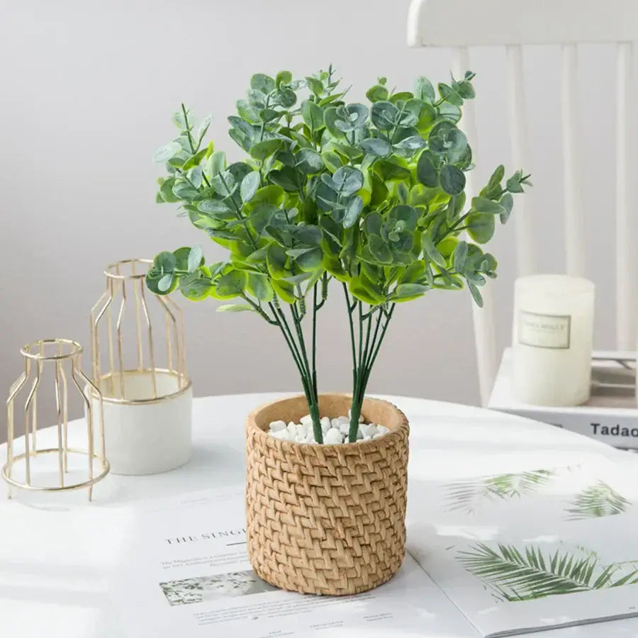 A lush green artificial eucalyptus leaves vase in a woven natural fiber pot with white pebbles for living room decor
