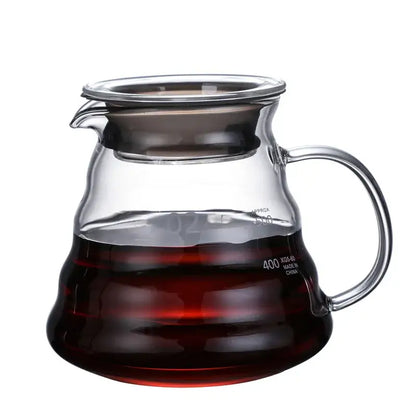 Clear glass ribbed coffee maker pot with curved handle and wood lid filled with dark brewed coffee for coffee brewing