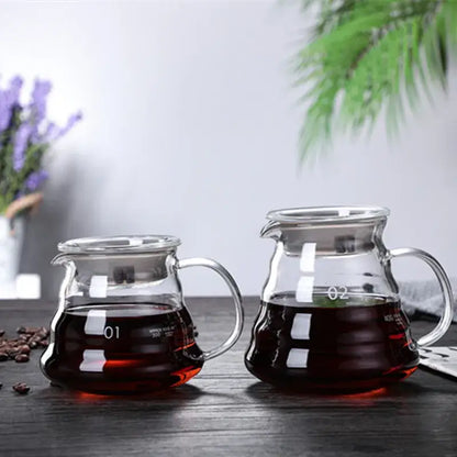 Two ribbed glass pour over coffee maker pots with wood lids filled with dark brewed coffee for coffee brewing