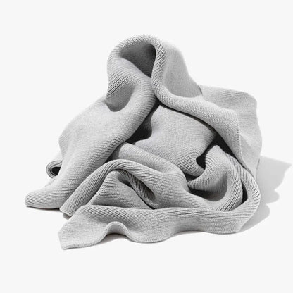 A soft light gray ribbed scarf paired with a ribbed gray organic cotton weighted blanket for bedroom use